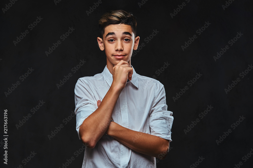 Handsome pensive young guy dressed in white shirt standing hand on chin. Isolated on a dark background. Handsome pensive young guy dressed in white shirt standing hand on chin. Isolated on a dark background.