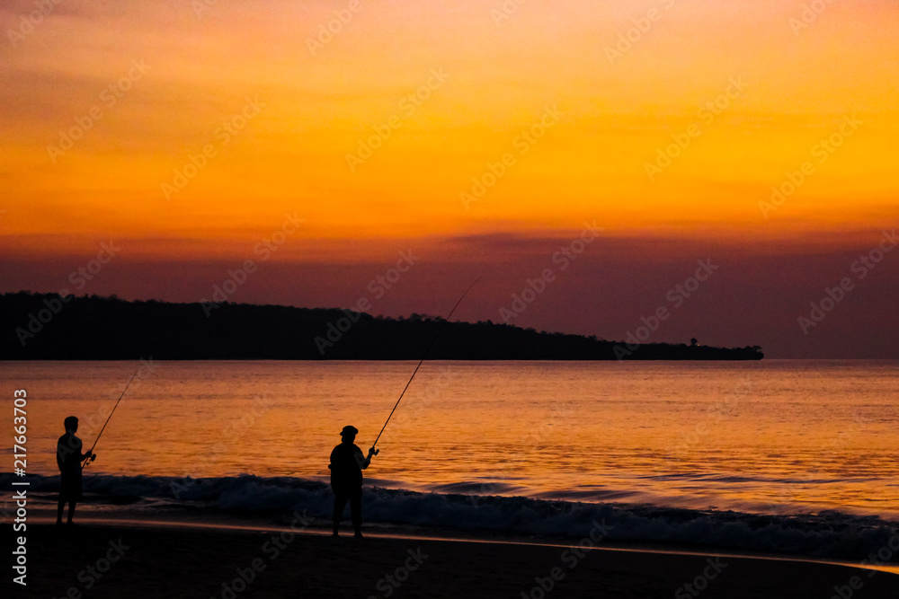 Fishermen on the beach on the island of Bali at sunset.