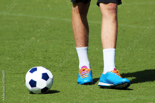 Men's feet and soccer ball on green field