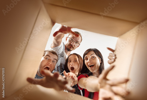 The surprised caucasian men and women opening carton box and looking inside. The package, delivery, surprise, gift, lifestyle concept