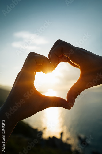 Two hands making heart shape in sky