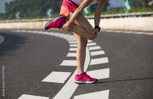 Woman runner with sports injured legs while running on highway