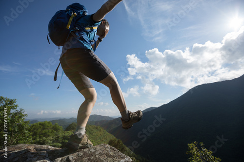 Woman hiker walking to the cliff edge on mountain top with eyes covered