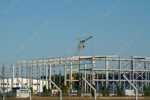 Construction of a logistics center of steel beams. Construction of metal structures. Construction of warehouses from a metal profile. Use of a tower crane when installing the frame of a building.