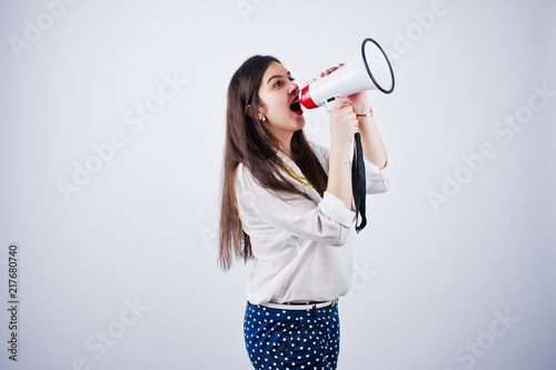 Portrait of a young woman in blue trousers and white blouse posing with megaphone in the studio. © AS Photo Family