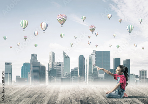 Fotografie Concept of careless happy childhood with girl pointing at someth