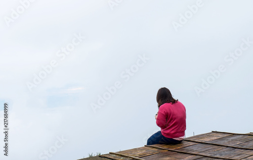 Back of pink shirt asian girl sitting at the outdoor with mist background