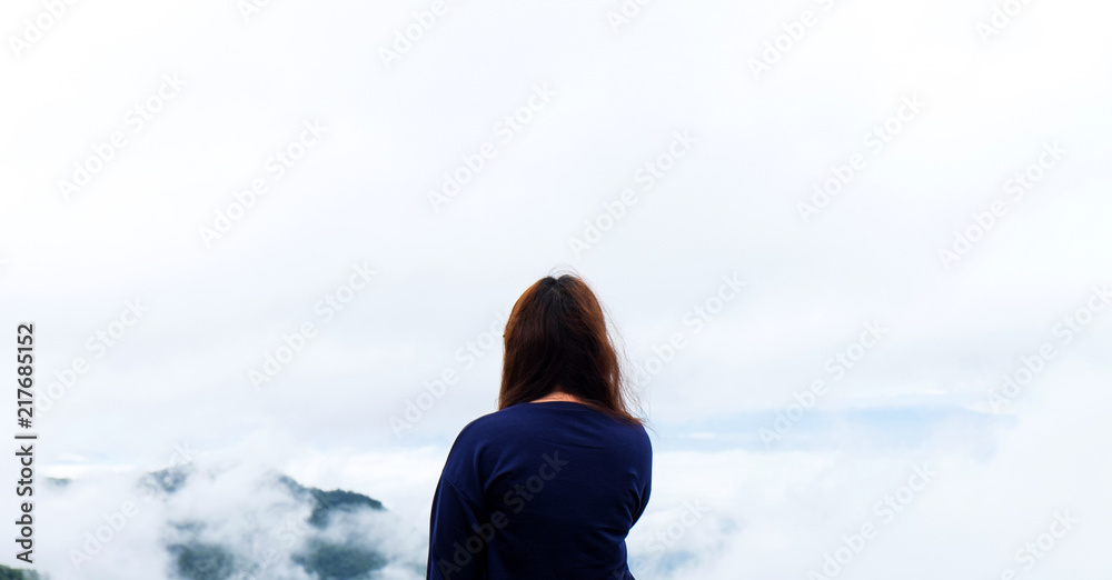 Back of a young pretty girl looking out of clouds sky