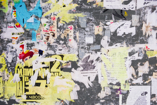 Billboard wall with torn and ragged glued advertisement posters. For background and texture