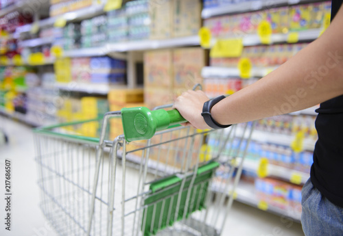 Closeup hand pushing shopping cart in groceries store