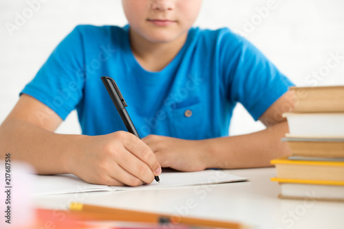 partial view of boy writing in copybook while doing homework at home