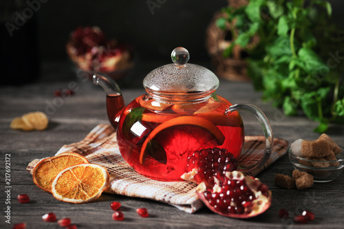 Pomegranate tea with orange on a wooden table in a rustic style