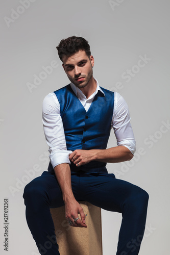 seated elegant man wearing a blue vest fixes his sleeves © Viorel Sima