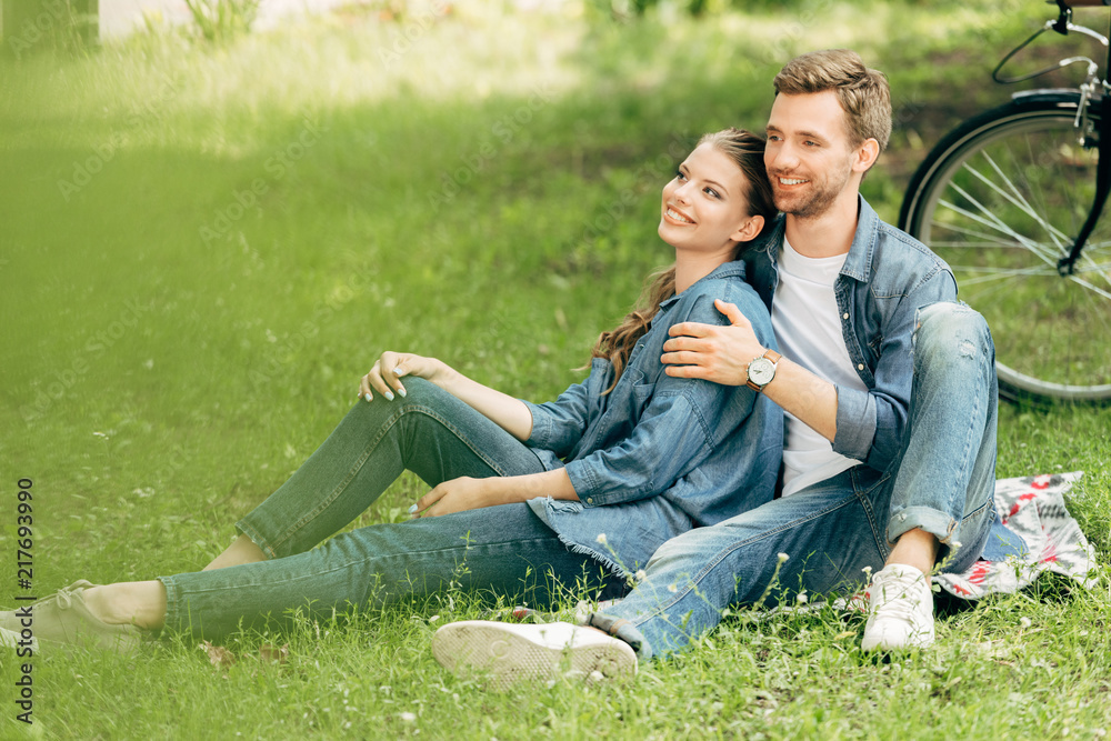 beautiful young couple sitting on grass at park together beautiful young couple sitting on grass at park together