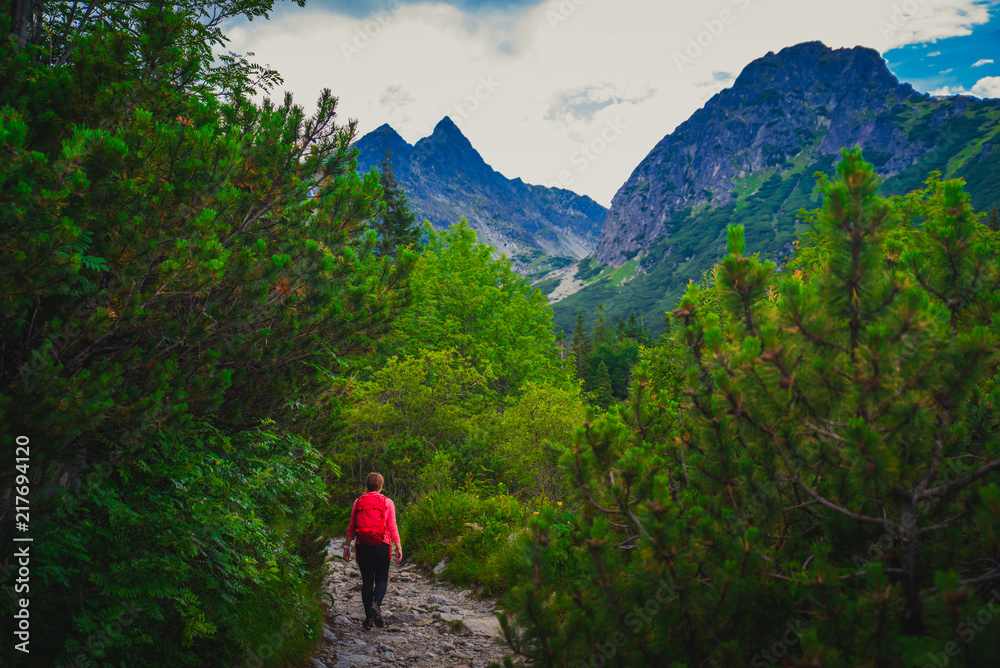 Female Tourist with red backpack in green nature