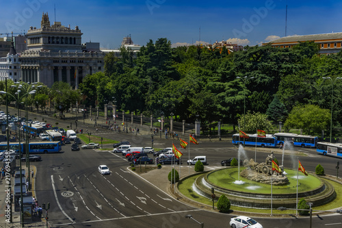 Madrid, Spain Ciberles Fountain with Spanish flags. Public buses and cars traffic around Plaza de Cibeles viewed from Cybele Palace at the Spanish capital.