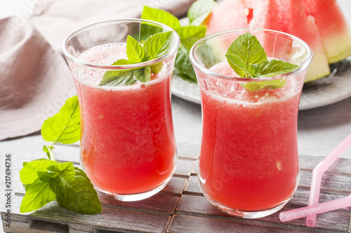 Fresh watermelon smoothie with ice and mint leaves in glasses.