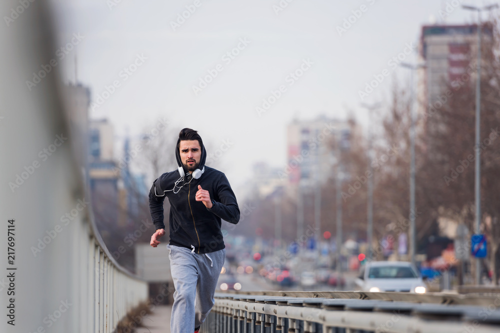 Hipster sports man jogging in city. Urban active life