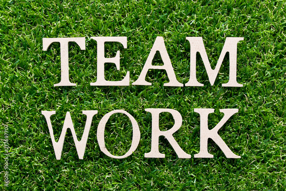 Wood alphabet in word teamwork on artificial green grass background Wood alphabet in word teamwork on artificial green grass background