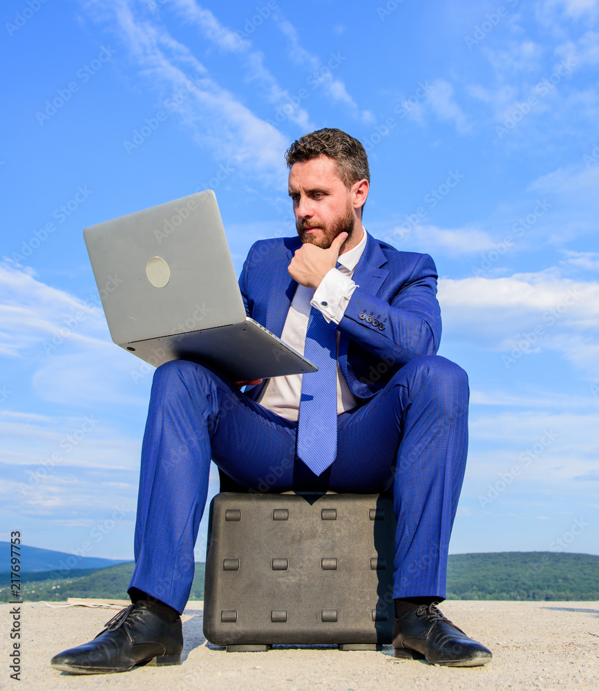 Businessman with laptop sit briefcase blue sky background. Laptop indispensable attribute modern businessman. Modern technologies portable device opportunity work worldwide. Business on fresh air