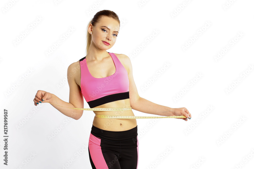 A sporty young girl measures a waist with a centimeter isolated on white background A sporty young girl measures a waist with a centimeter isolated on white background