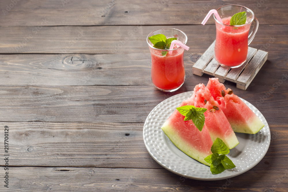 Watermelon sliced on a plate with mint leaves and fresh watermelon smoothie on a wooden background. Copy space Watermelon sliced on a plate with mint leaves and fresh watermelon smoothie on a wooden background. Copy space