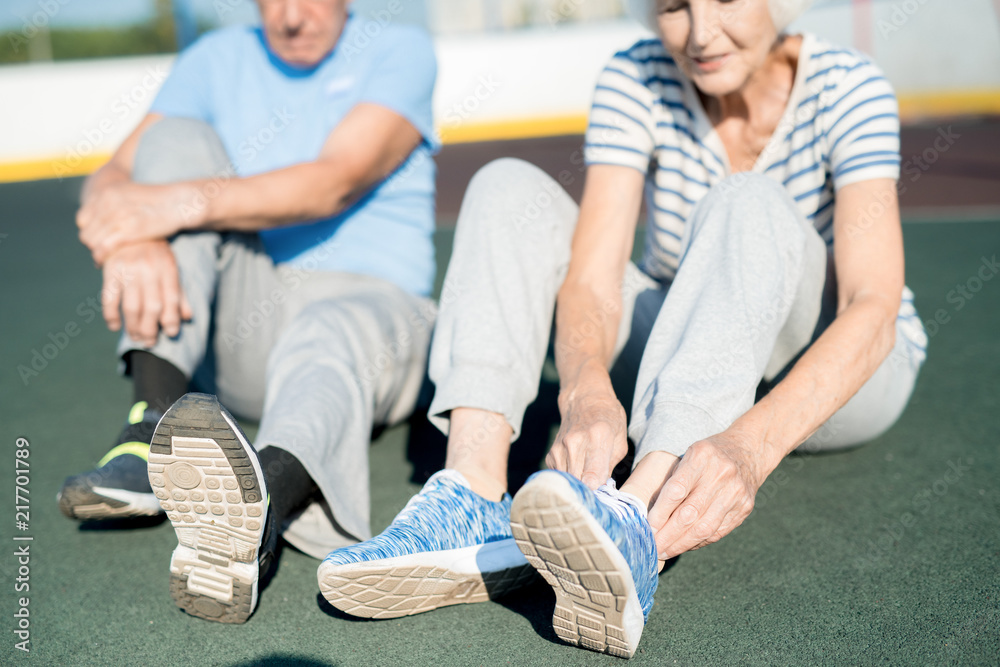 Φωτογραφία Mid section portrait of white haired senior couple tying sports shoes sitting on
