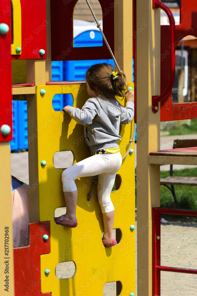 Little children run around and play in the playground. Game center for a young child. Little girl is playing outdoors. The concept of summer children's entertainment. Little children run around and play in the playground. Game center for a young child. Little girl is playing outdoors. The concept of summer children's entertainment.