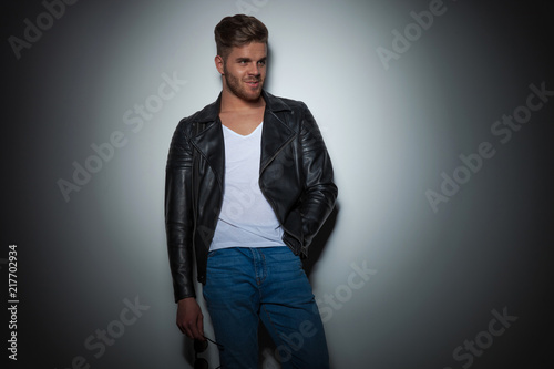 handsome young man in leather jacket leaning against the wall