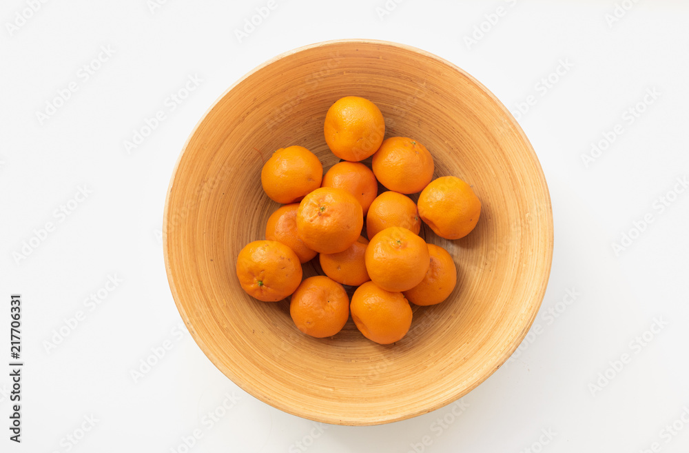 Top down view of orange mandarines in bamboo bowl on white table Top down view of orange mandarines in bamboo bowl on white table