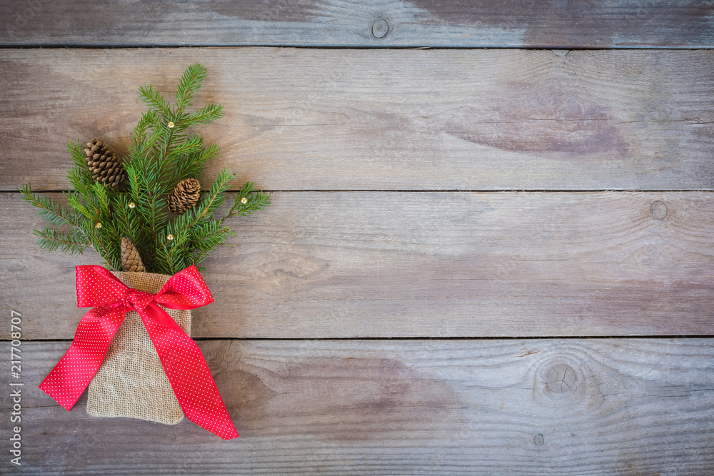 Christmas Firbranch with cones, red polka dot ribbon in the rustic bag on old wooden background Christmas Firbranch with cones, red polka dot ribbon in the rustic bag on old wooden background