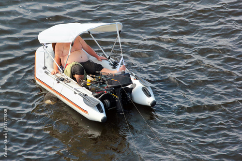 Fisherman in a rubber motor boat with fishing tackle and rods
