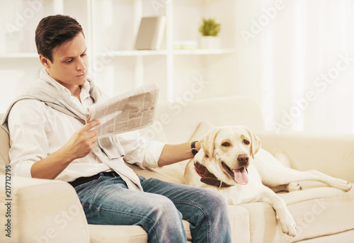 Wallpaper Mural Young Man Sitting on White Sofa with Dog at Home. Torontodigital.ca