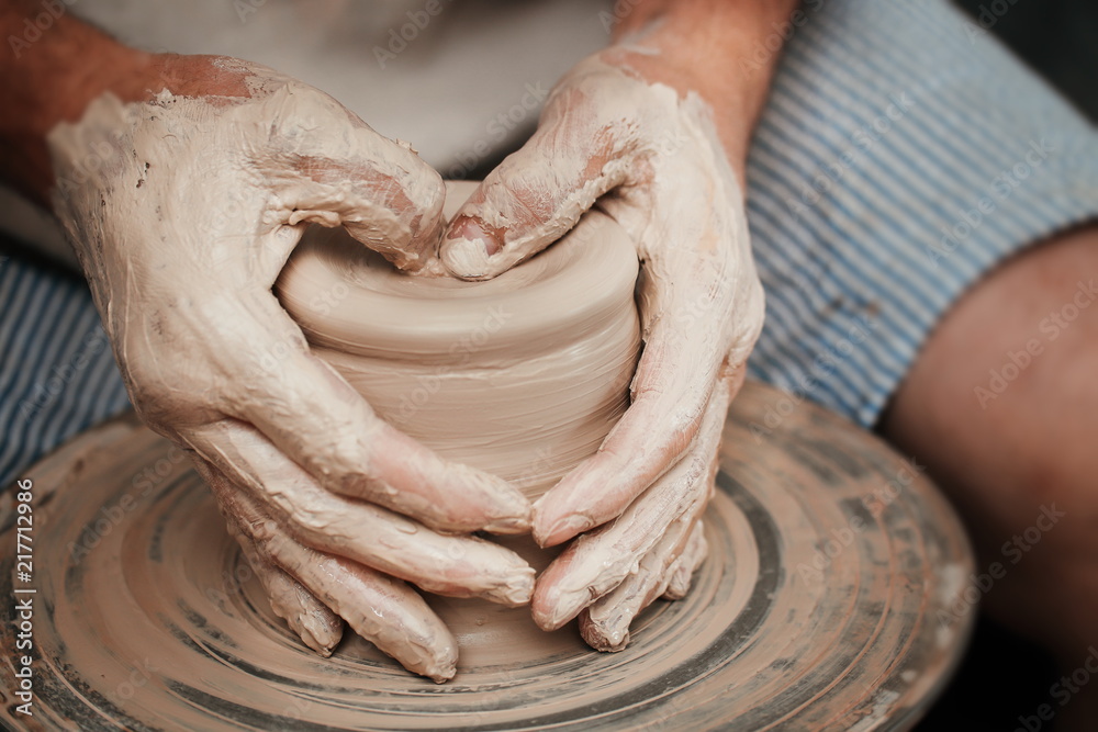 Fototapeta premium hands of a potter, creating an earthen jar on the circle 