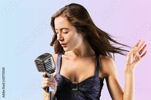 Young woman singing with microphone on blurred
