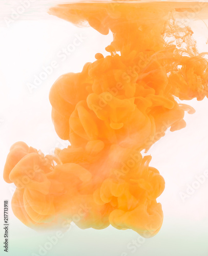 Orange paint in the water. Abstract grey background with Ink swirling in water. 