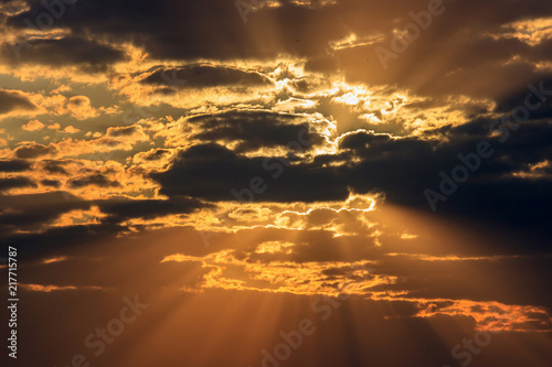 Dramatic orange sky with dark clouds and rays of the sun at sunset
