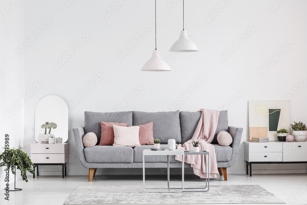 Real photo of an elegant living room interior with a grey sofa, pink pillows, cabinets and lamps - obrazy, fototapety, plakaty 