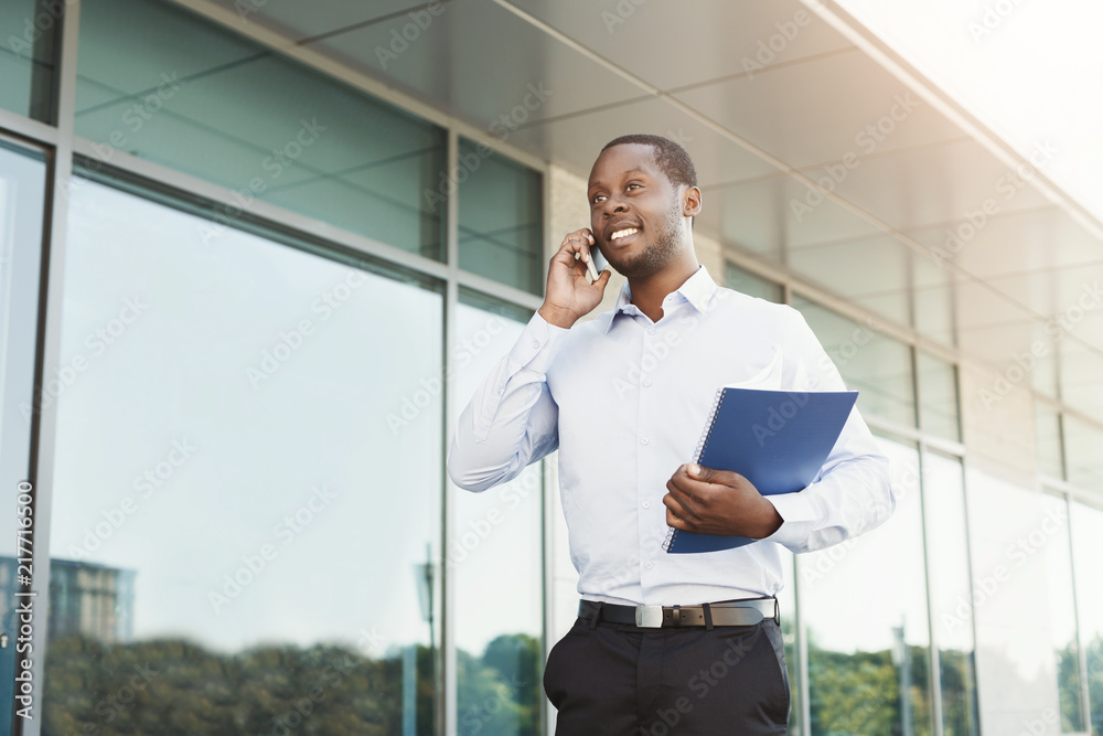 Fototapeta premium Busy black businessman outdoors in smart casual ware