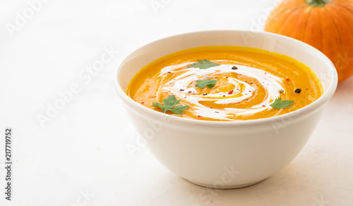 Pumpkin soup with cream and pumpkin seeds isolated on white background. Autumn concept.