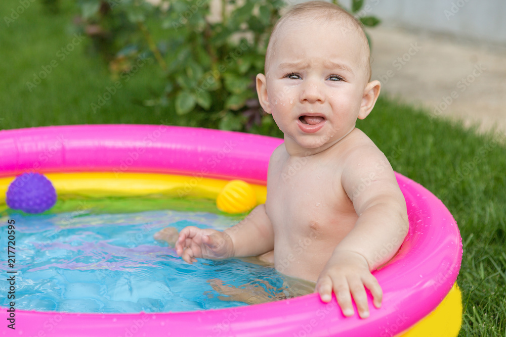 A small child is bathing in a pool, inflatable children's inflatable pool in summer A small child is bathing in a pool, inflatable children's inflatable pool in summer