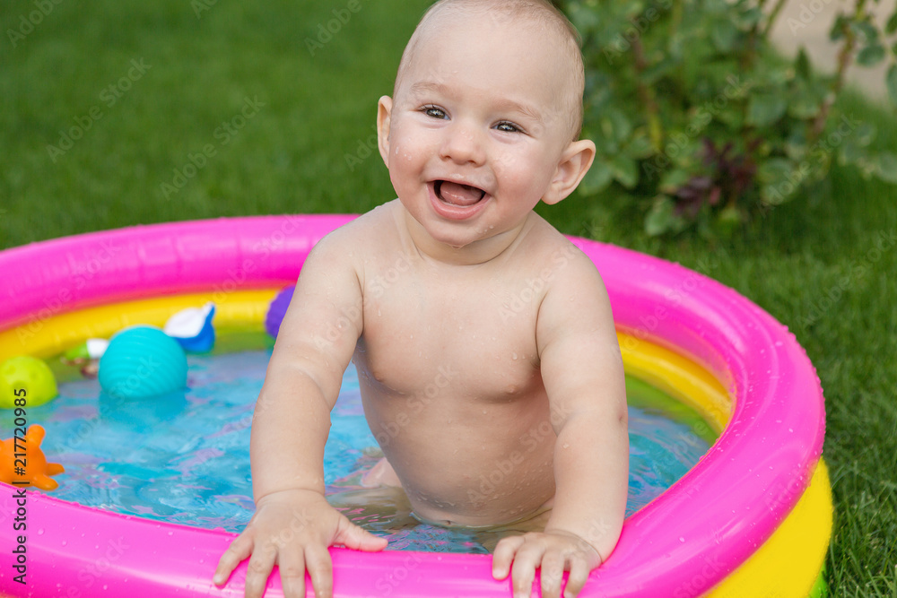 A small child is bathing in a pool, inflatable children's inflatable pool in summer A small child is bathing in a pool, inflatable children's inflatable pool in summer