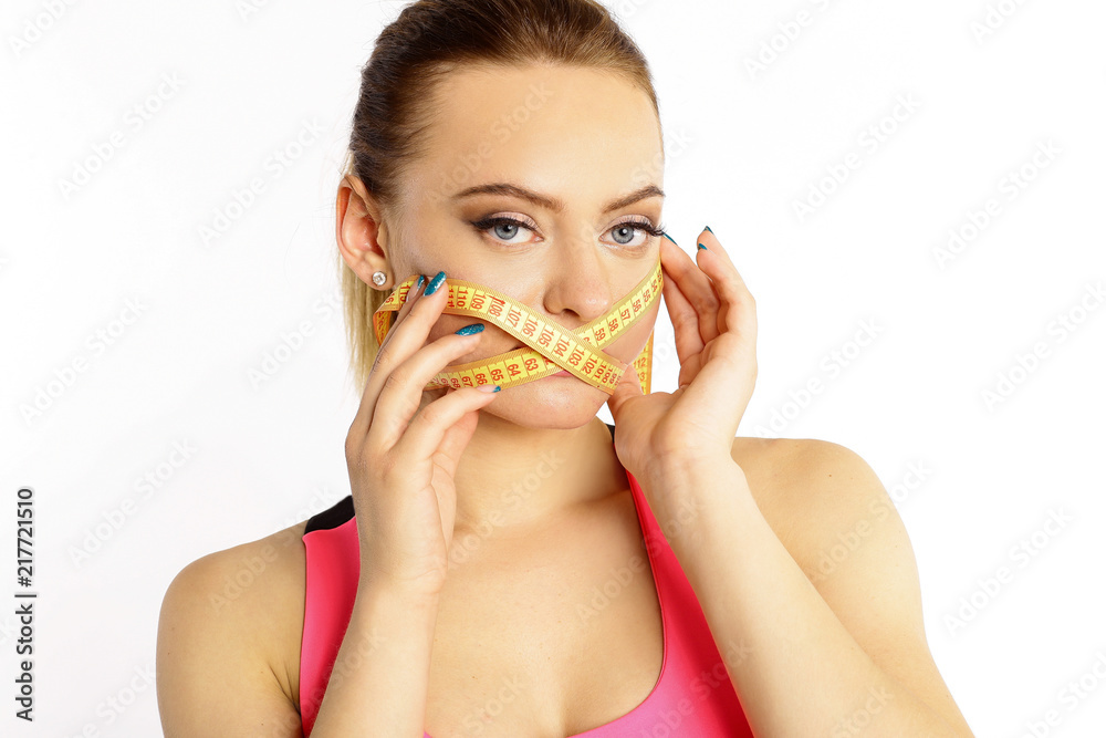 A woman with a yellow measuring tape around her mouth, a centimeter isolated on white background. Do not eat to be thin A woman with a yellow measuring tape around her mouth, a centimeter isolated on white background. Do not eat to be thin