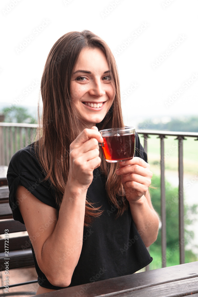 Beautiful young woman holds cup of tea and smiling