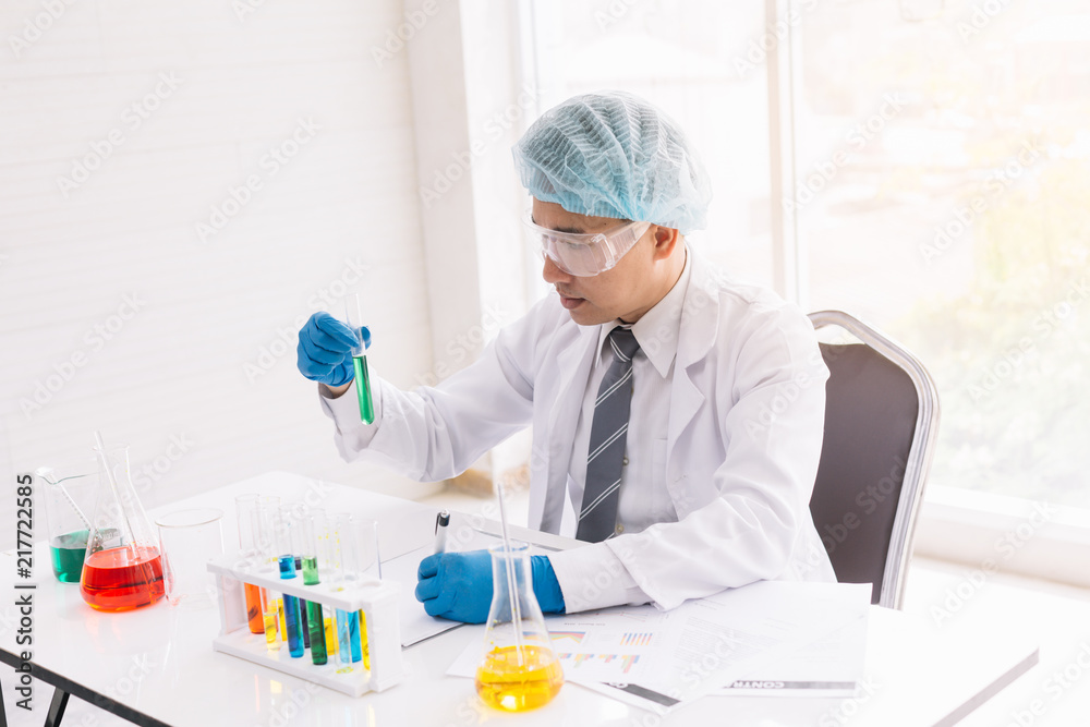 Medical scientist, or medical researcher looking at a test tube containing a clear solution in a laboratory. Medical scientist, or medical researcher looking at a test tube containing a clear solution in a laboratory.