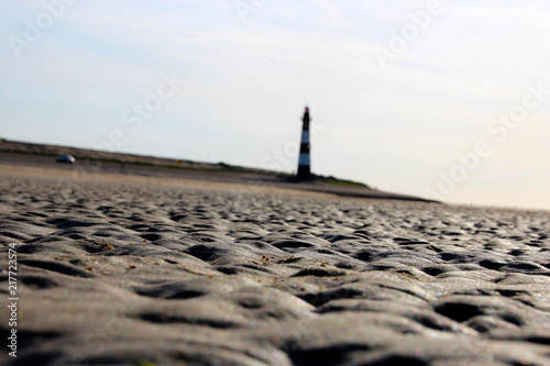 Leuchtturm am Strand mit Wellen im Sand