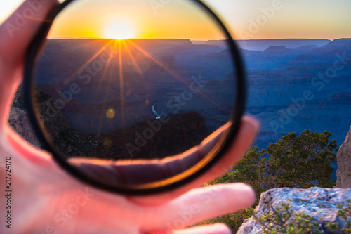 Foto Girls hand holding warming, neutral density or polarizing high quality glass filter to put on her camera lens in Grand Canyon with Colorado river sunset landscape