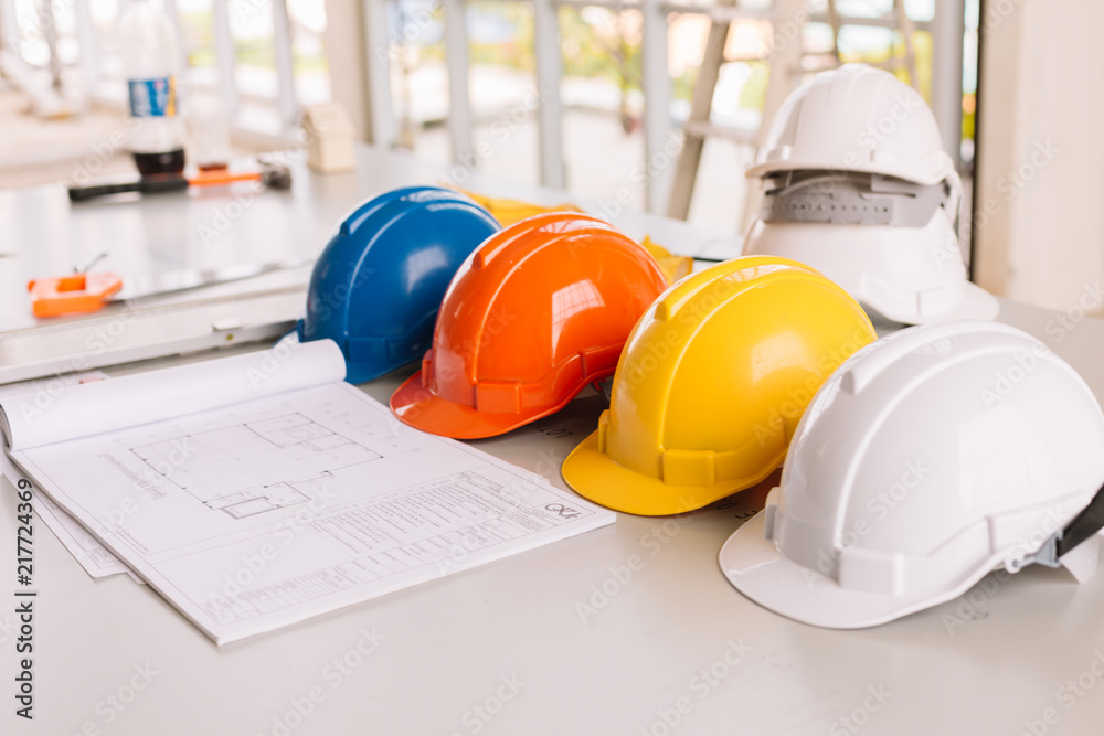 Yellow,white, Blue, Orange helmet safety engineer for project engineering.On the floor of the desk. Yellow,white, Blue, Orange helmet safety engineer for project engineering.On the floor of the desk.