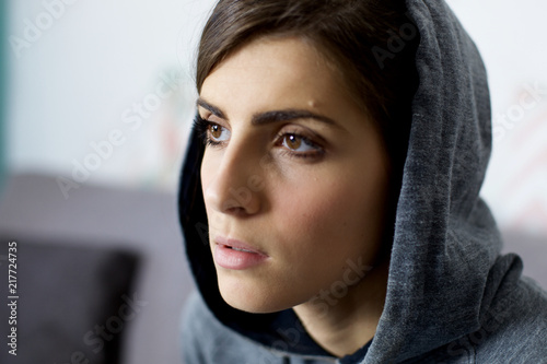 Sad young woman with hood thinking feeling lost closeup