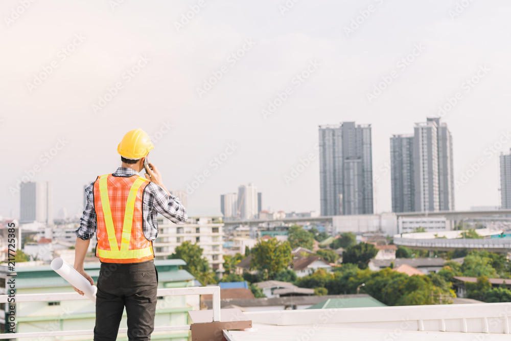 Engineers stand on tall buildings and talk about cell phones in the field of construction.Concepts of work on building construction, building background